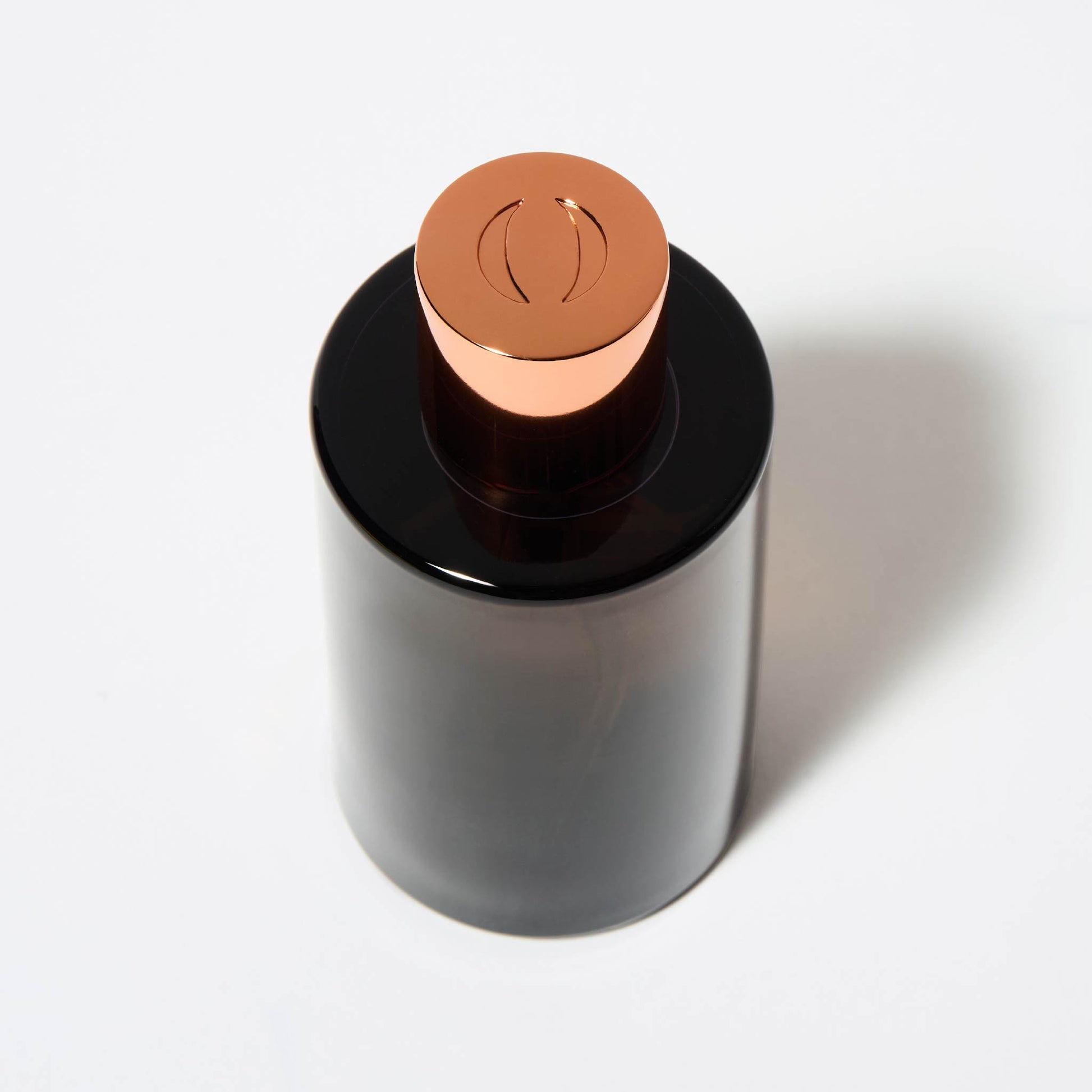 Top view of OJAR perfume bottle in black with letter o engraved on the copper cap on a white background.