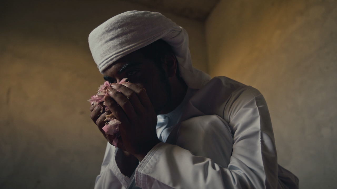 an omani man with handful of roses admiring the fragrance
